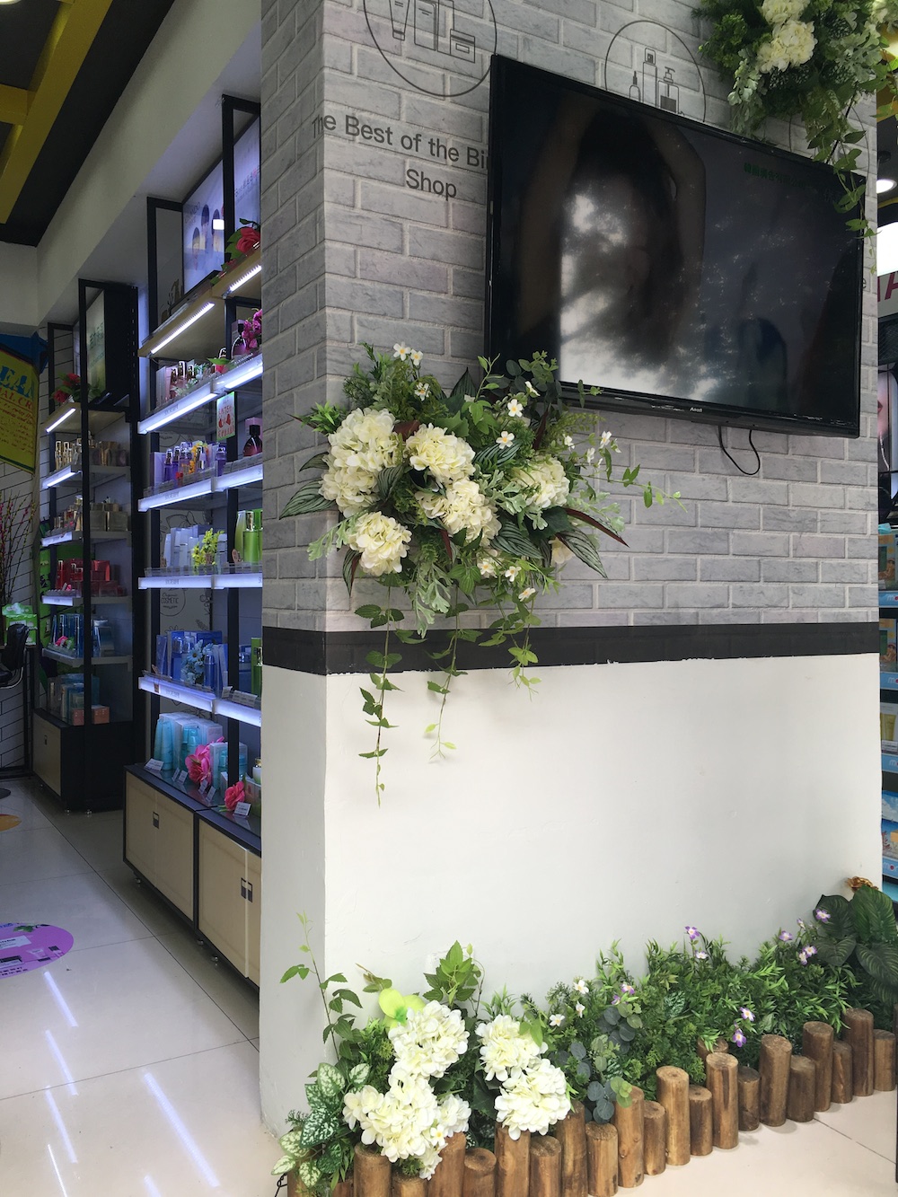 护肤区和另一个区域之间有一堵灰白色砖墙，悬挂着一个显示屏，用于播放各种潮流影音录像，增强时尚感。