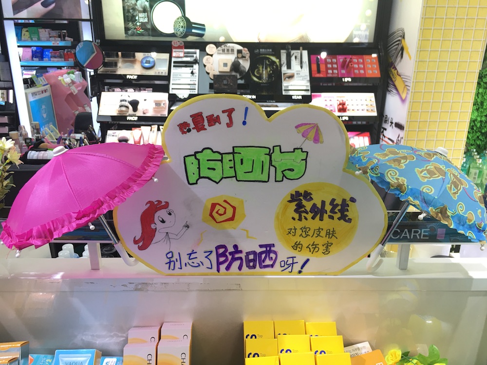 而作为主推应季品，防晒产品中岛上方也有店员自制的“洋伞”装饰以及防晒POP，萌萌的形象直击顾客内心。